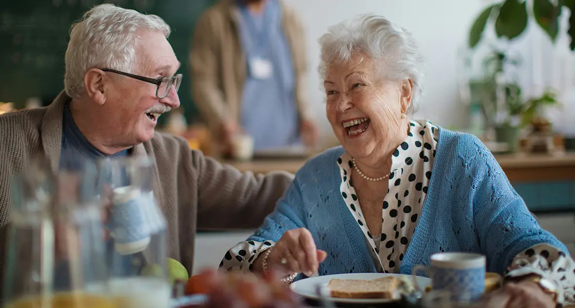 An old man and a woman talking to each other at a nursing home.